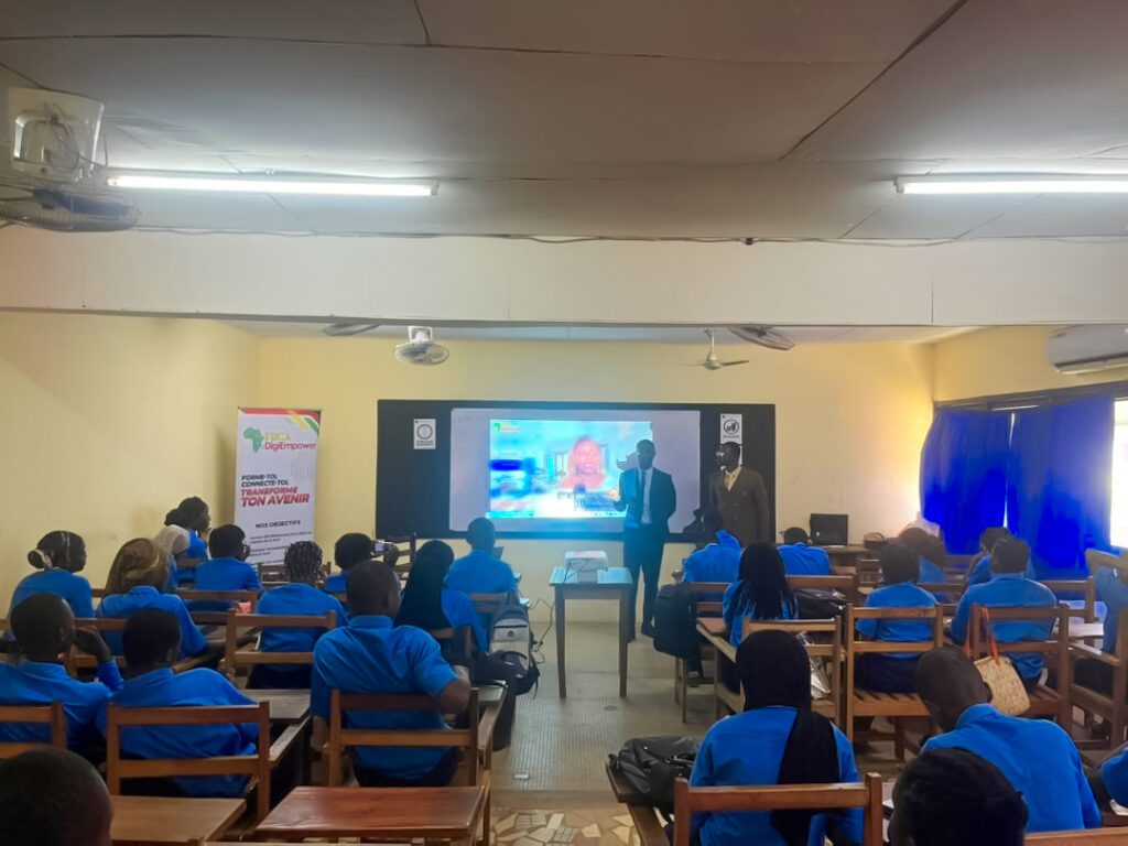 Groupe d'élèves en uniforme bleu et cravate rouge, posant avec plusieurs adultes devant un bâtiment blanc. Dans le cadre de son programme phare Africa DigiEmpower, THEYA by Cybastion a déployé du 24 au 27 mars 2026 une mission de formation d'envergure à San Pedro, formateurs et encadrants a sillonné les établissements de la ville pour offrir des formations gratuites et certifiantes aux étudiants et jeunes de la région-Africa DigiEmpower formations gratuites pour les jeunes. design by adambita237