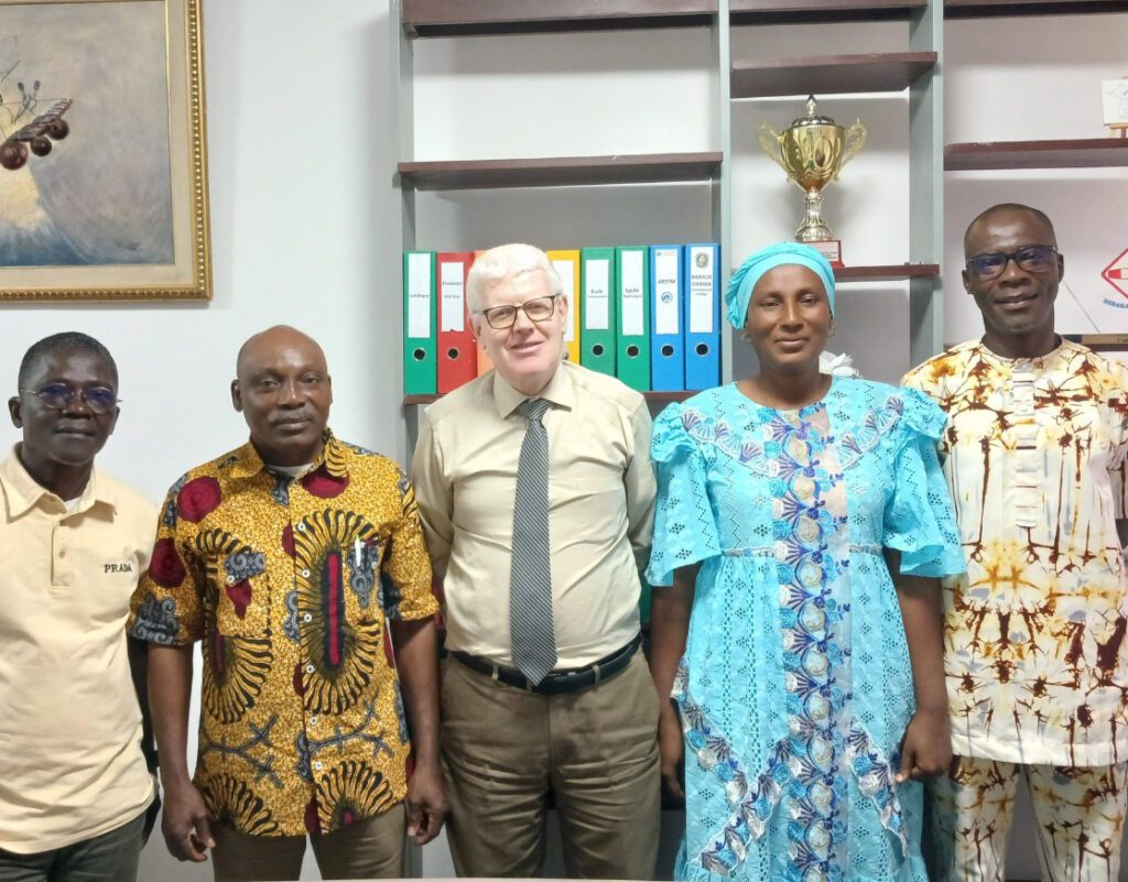 Groupe d'élèves en uniforme bleu et cravate rouge, posant avec plusieurs adultes devant un bâtiment blanc. Dans le cadre de son programme phare Africa DigiEmpower, THEYA by Cybastion a déployé du 24 au 27 mars 2026 une mission de formation d'envergure à San Pedro, formateurs et encadrants a sillonné les établissements de la ville pour offrir des formations gratuites et certifiantes aux étudiants et jeunes de la région-Africa DigiEmpower formations gratuites pour les jeunes. design by adambita237