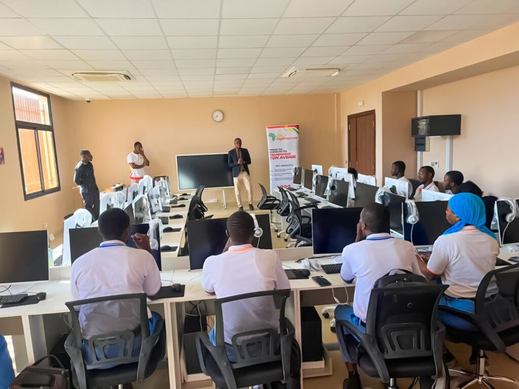 Groupe d'élèves en uniforme bleu et cravate rouge, posant avec plusieurs adultes devant un bâtiment blanc. Dans le cadre de son programme phare Africa DigiEmpower, THEYA by Cybastion a déployé du 24 au 27 mars 2026 une mission de formation d'envergure à San Pedro, formateurs et encadrants a sillonné les établissements de la ville pour offrir des formations gratuites et certifiantes aux étudiants et jeunes de la région-Africa DigiEmpower formations gratuites pour les jeunes. design by adambita237