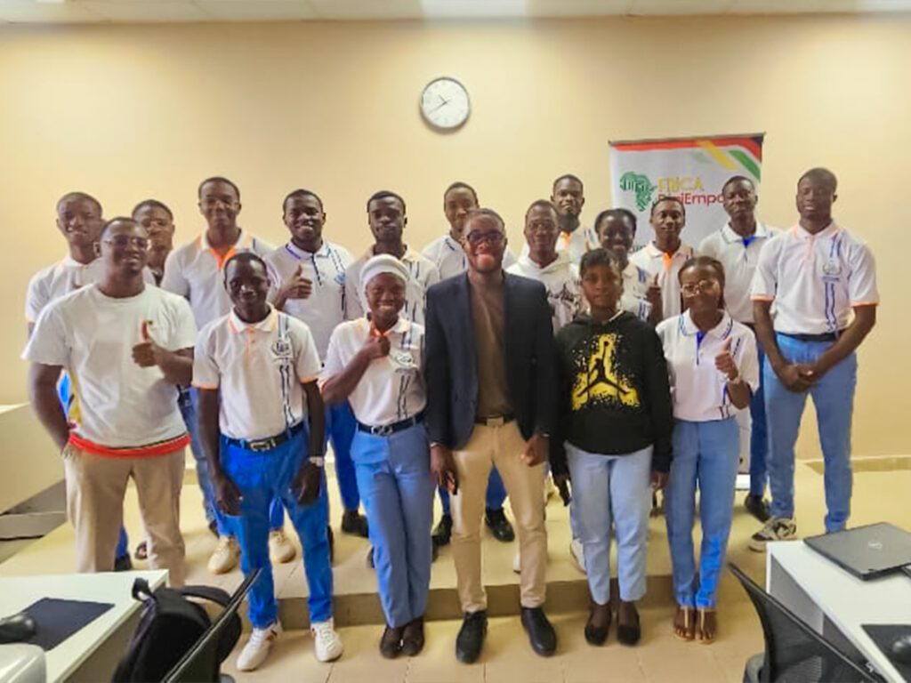 Groupe d'élèves en uniforme bleu et cravate rouge, posant avec plusieurs adultes devant un bâtiment blanc. Dans le cadre de son programme phare Africa DigiEmpower, THEYA by Cybastion a déployé du 24 au 27 mars 2026 une mission de formation d'envergure à San Pedro, formateurs et encadrants a sillonné les établissements de la ville pour offrir des formations gratuites et certifiantes aux étudiants et jeunes de la région-Africa DigiEmpower formations gratuites pour les jeunes. design by adambita237